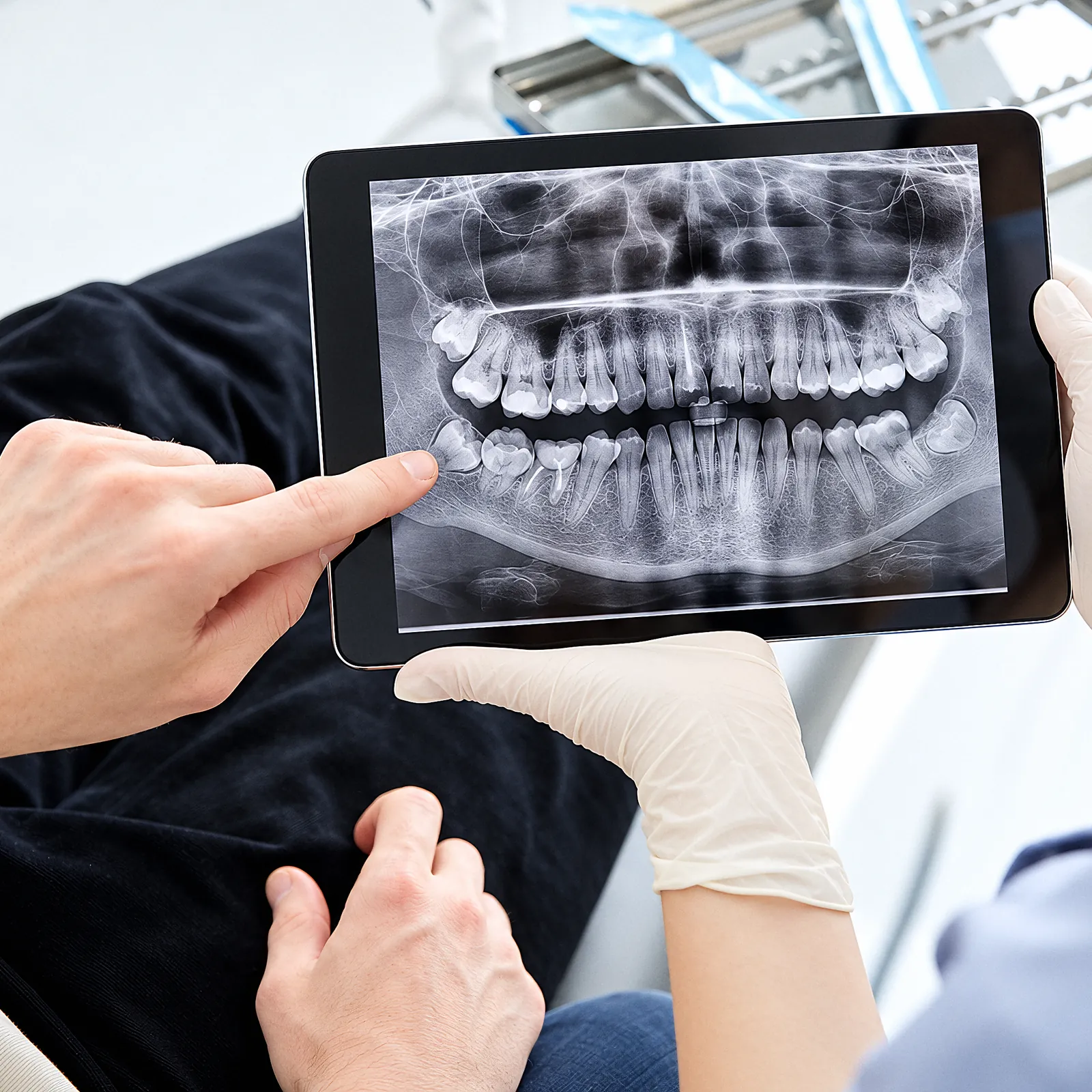 A dentist pointing to a panoramic X-ray on a tablet
