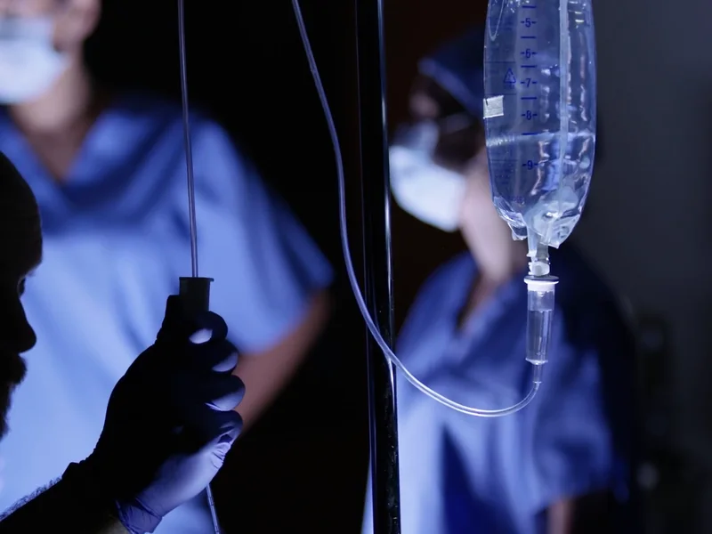 An IV drip beside a patient while the care team watches