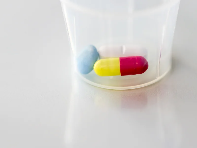 Capsules and tablets in a clear medicine cup