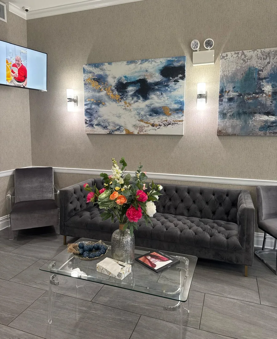 The waiting-room lounge: grey sofas, abstract paintings and flowers