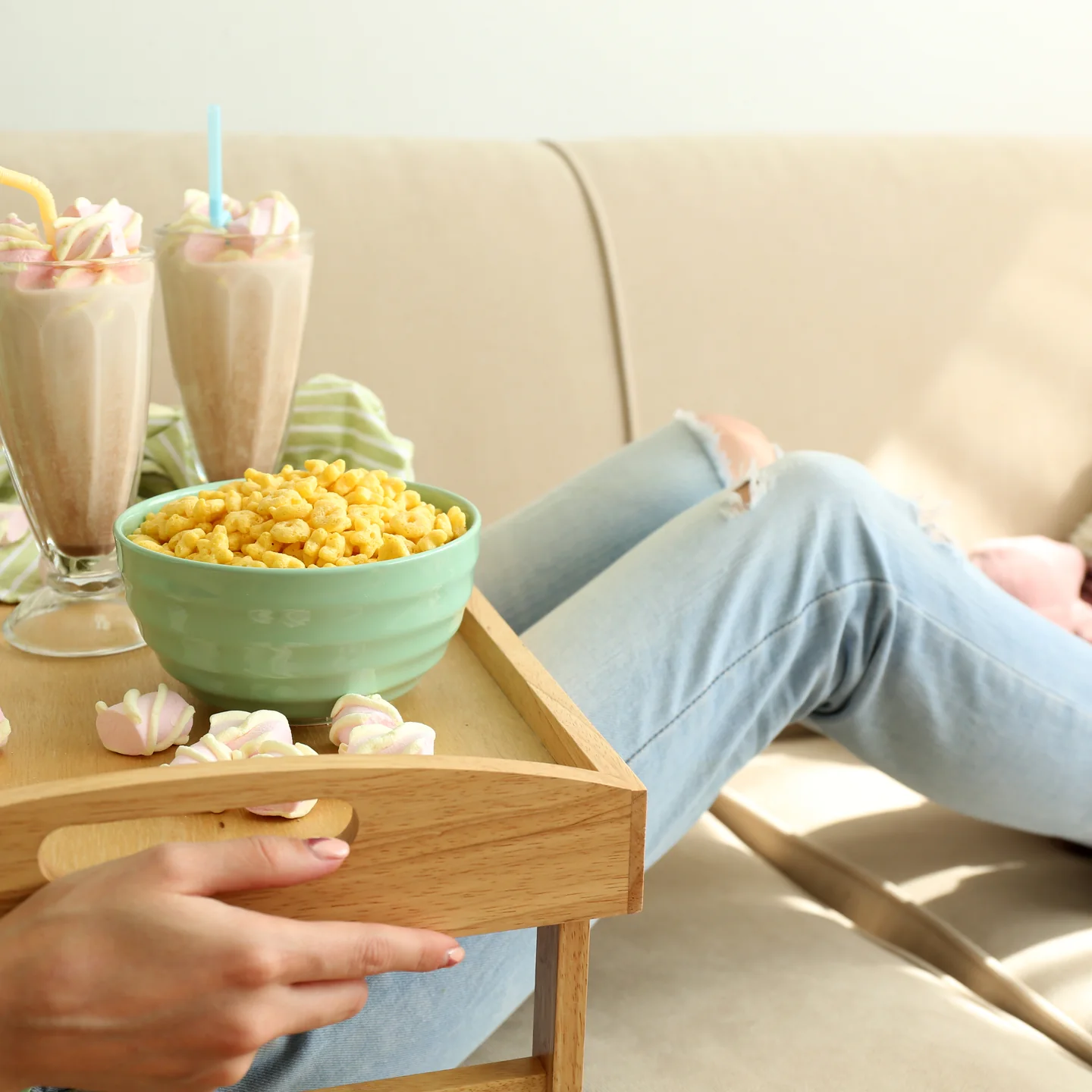 Smoothies and a bowl of soft cereal on a tray beside the sofa