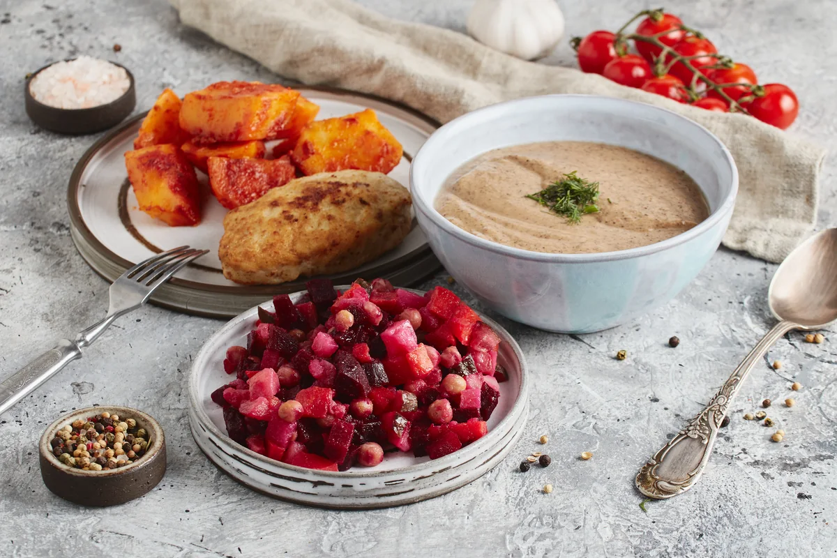 Bowls of soup, mashed sweet potato and raspberries on a stone table