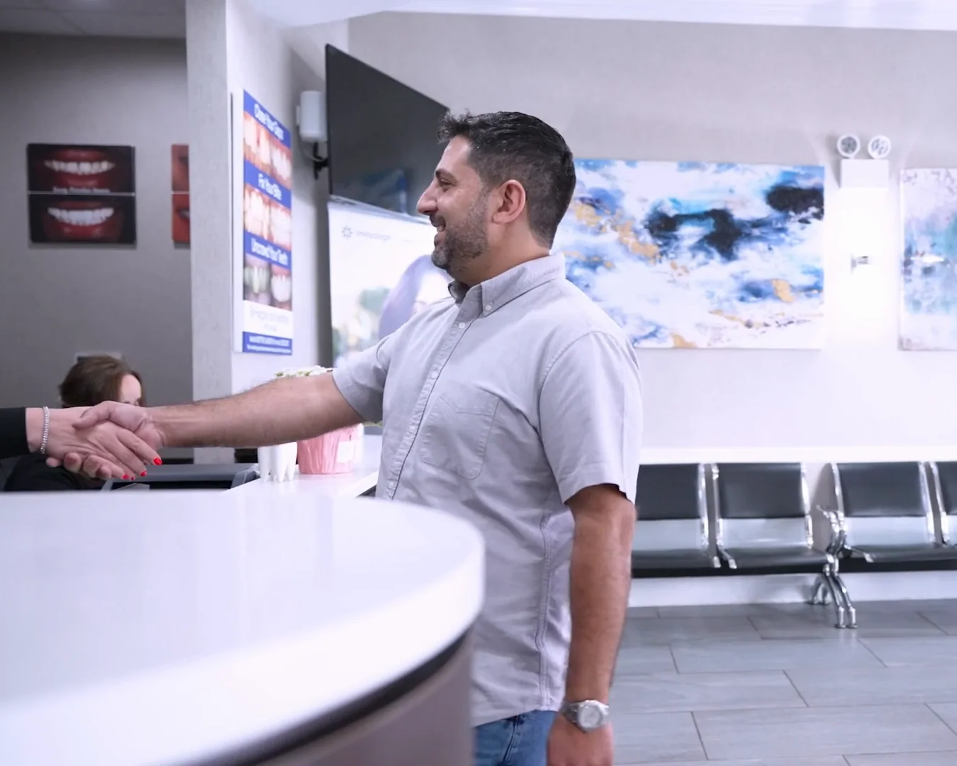 A patient shaking hands with the front-desk team at reception