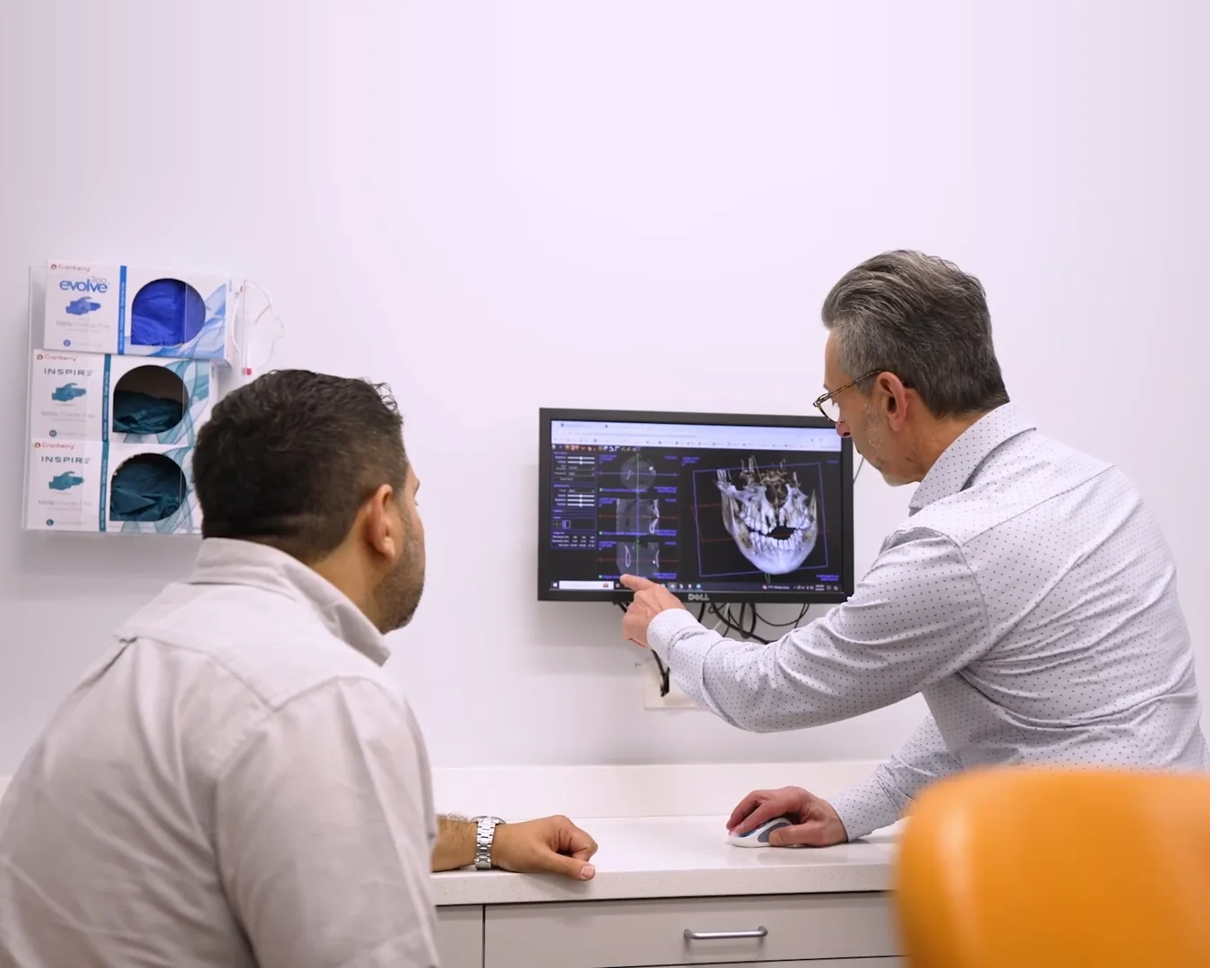 A patient and a dentist looking at his 3D scan on a monitor in a treatment room