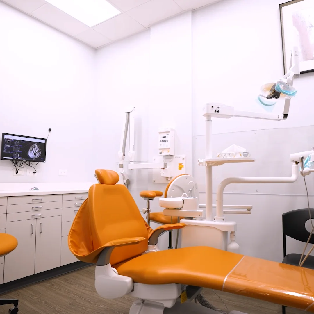 A treatment room with an orange dental chair