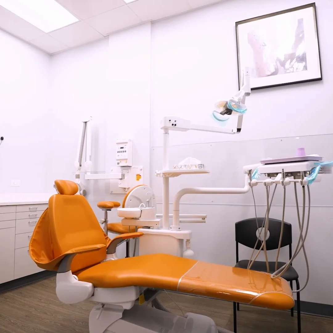 A treatment room with two orange chairs and a screen on the wall