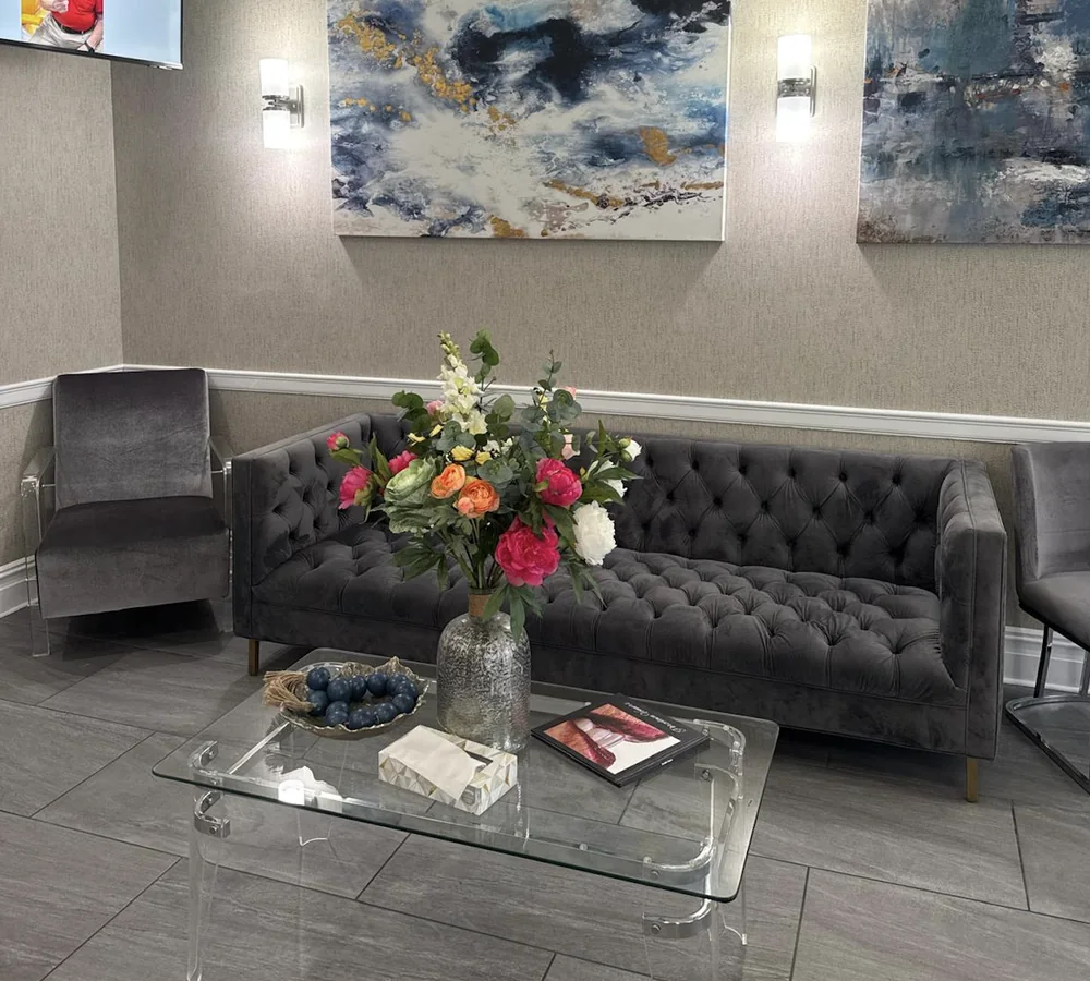 The waiting-room lounge: dark tufted seating and flowers on the table