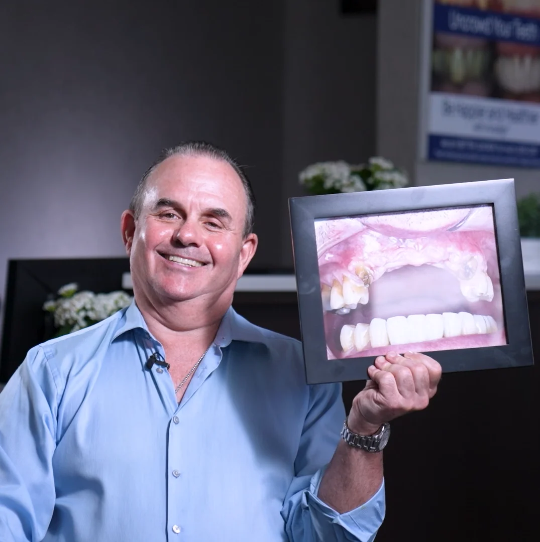 Daniel, a patient of the practice, holding a photograph of his teeth before treatment